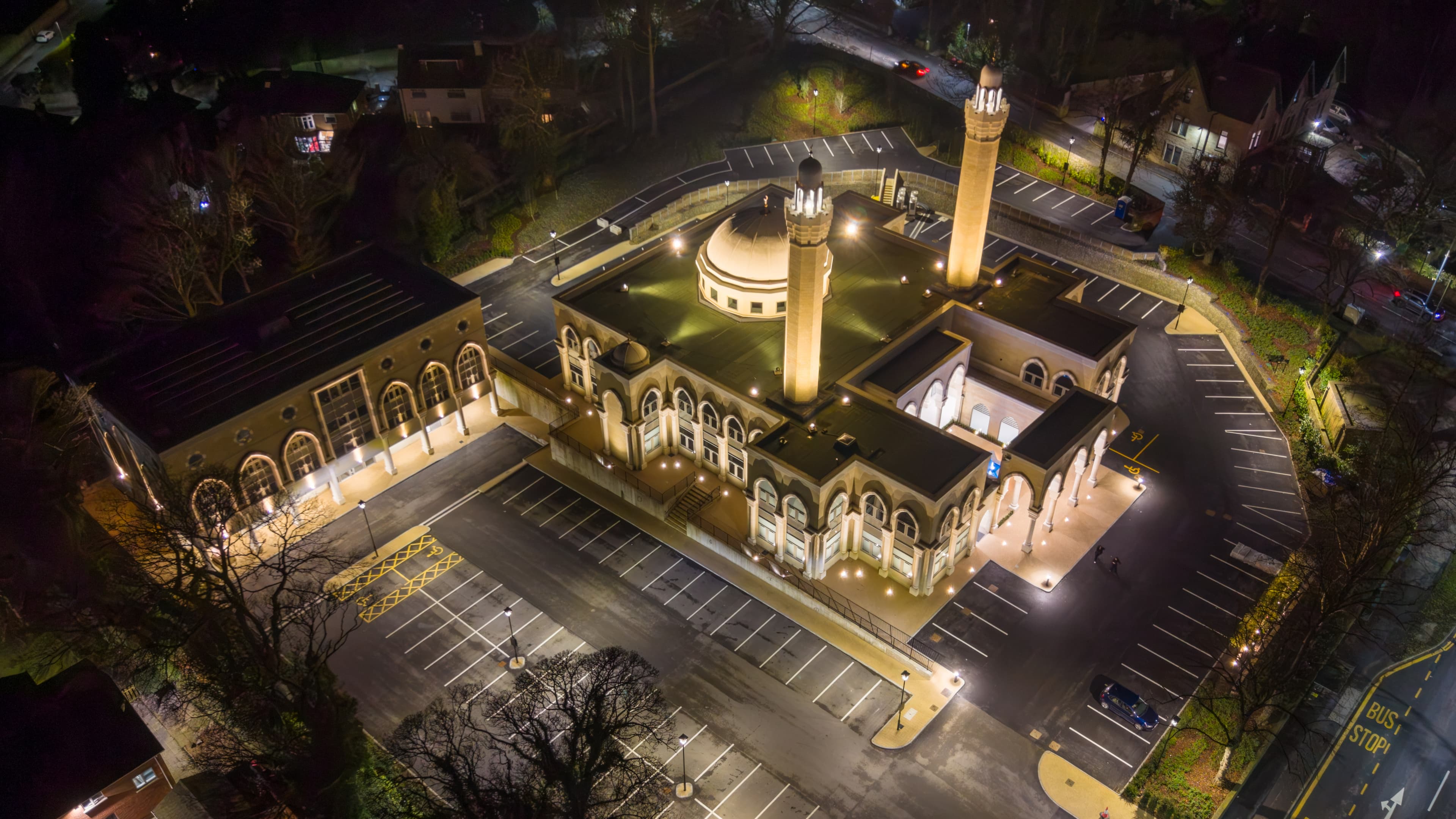 The masjid complex from the air at night, floodlit, showing the dome and the twin minarets