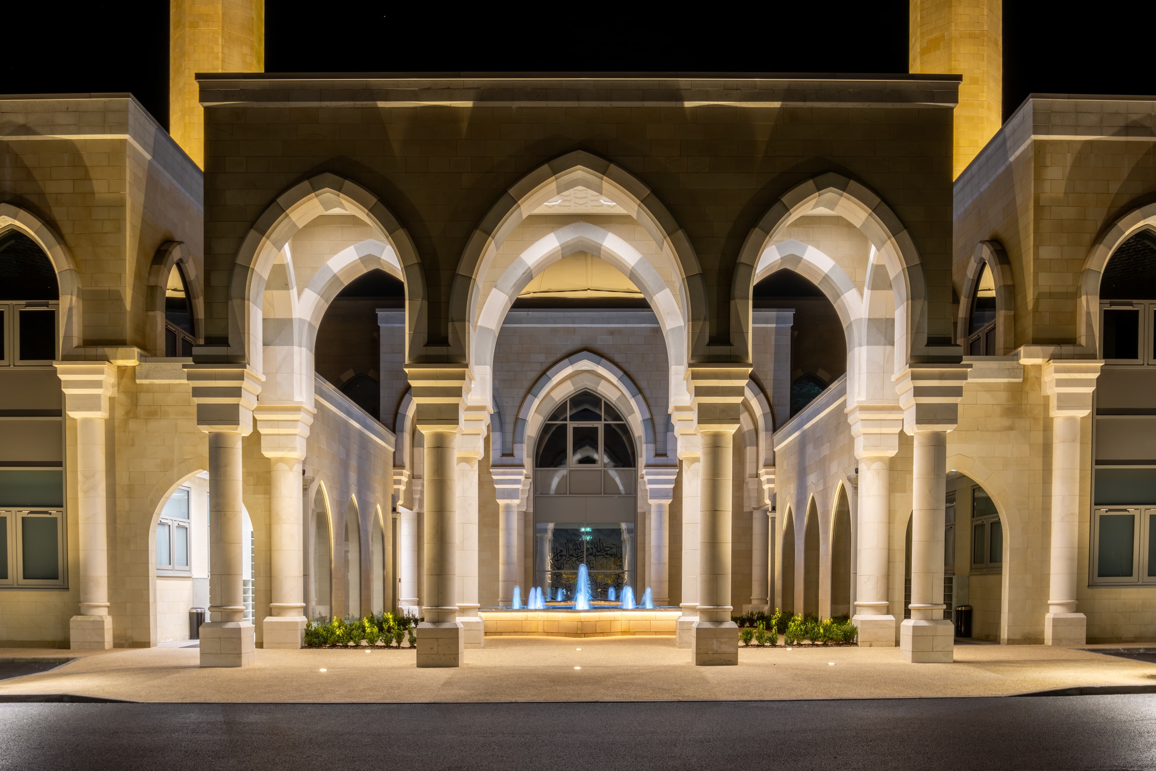 The courtyard arcade of pointed arches, lit warmly at night