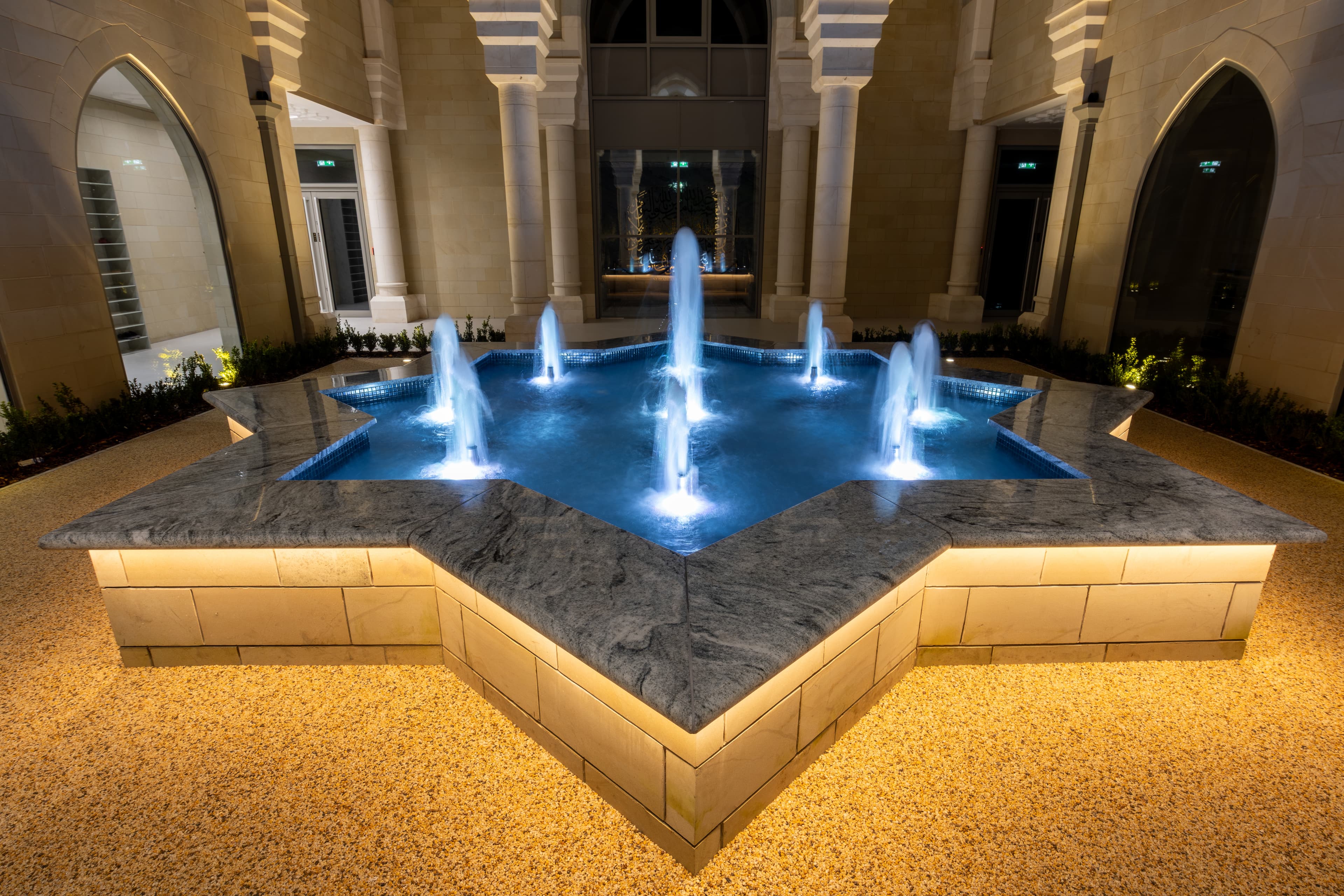The eight-pointed star fountain in the courtyard, lit blue