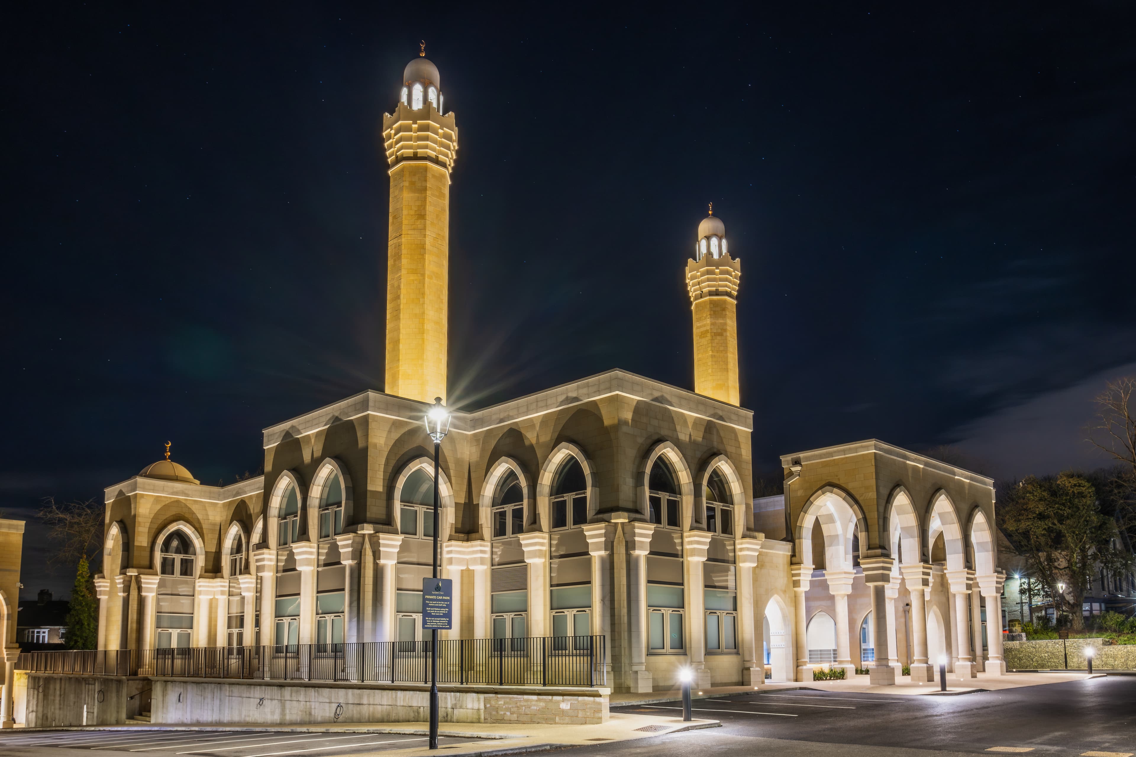 The mosque exterior at blue hour, one tall minaret rising against a deep blue evening sky.