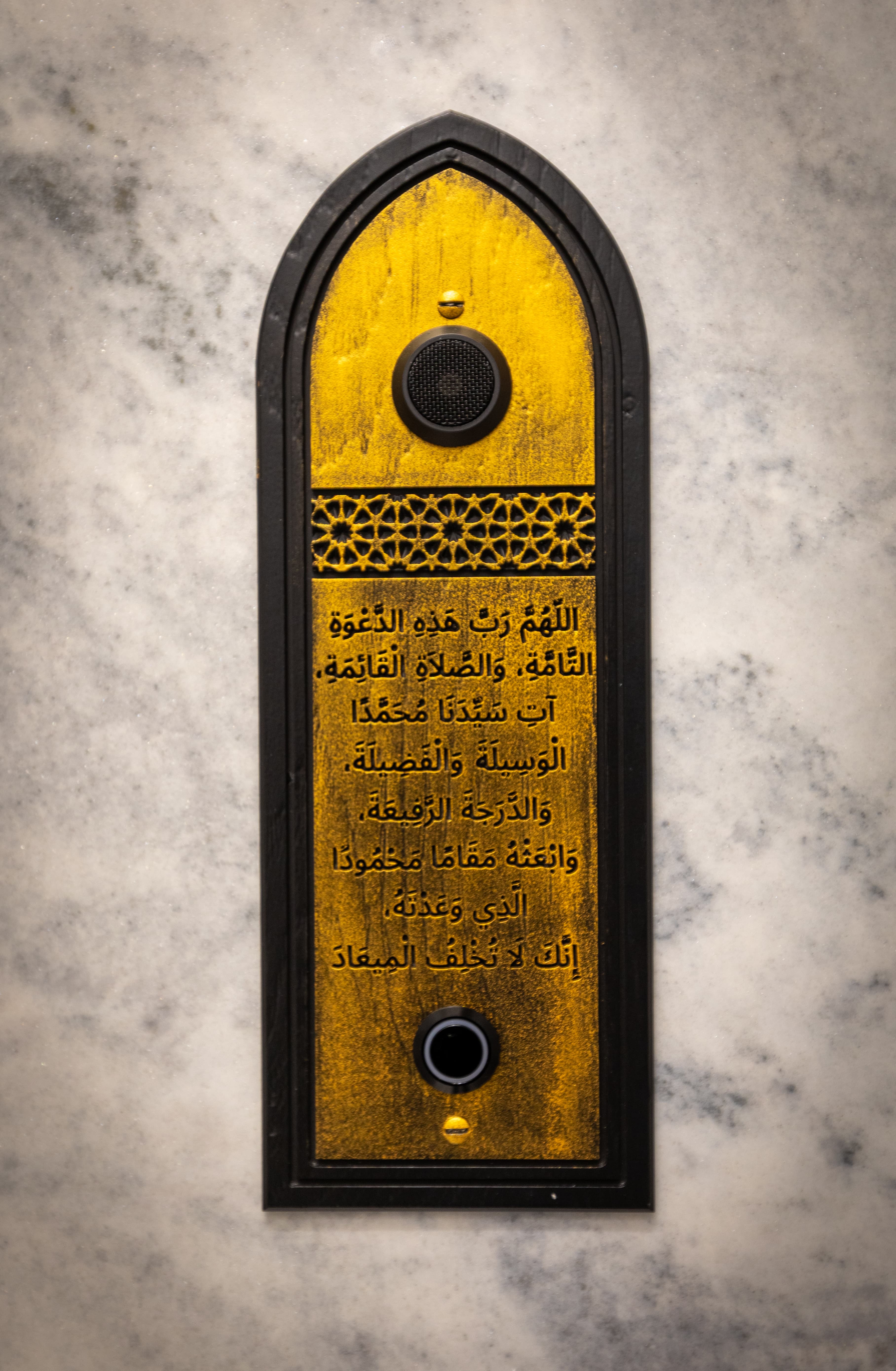 A tall gold calligraphy panel mounted on a marble wall.