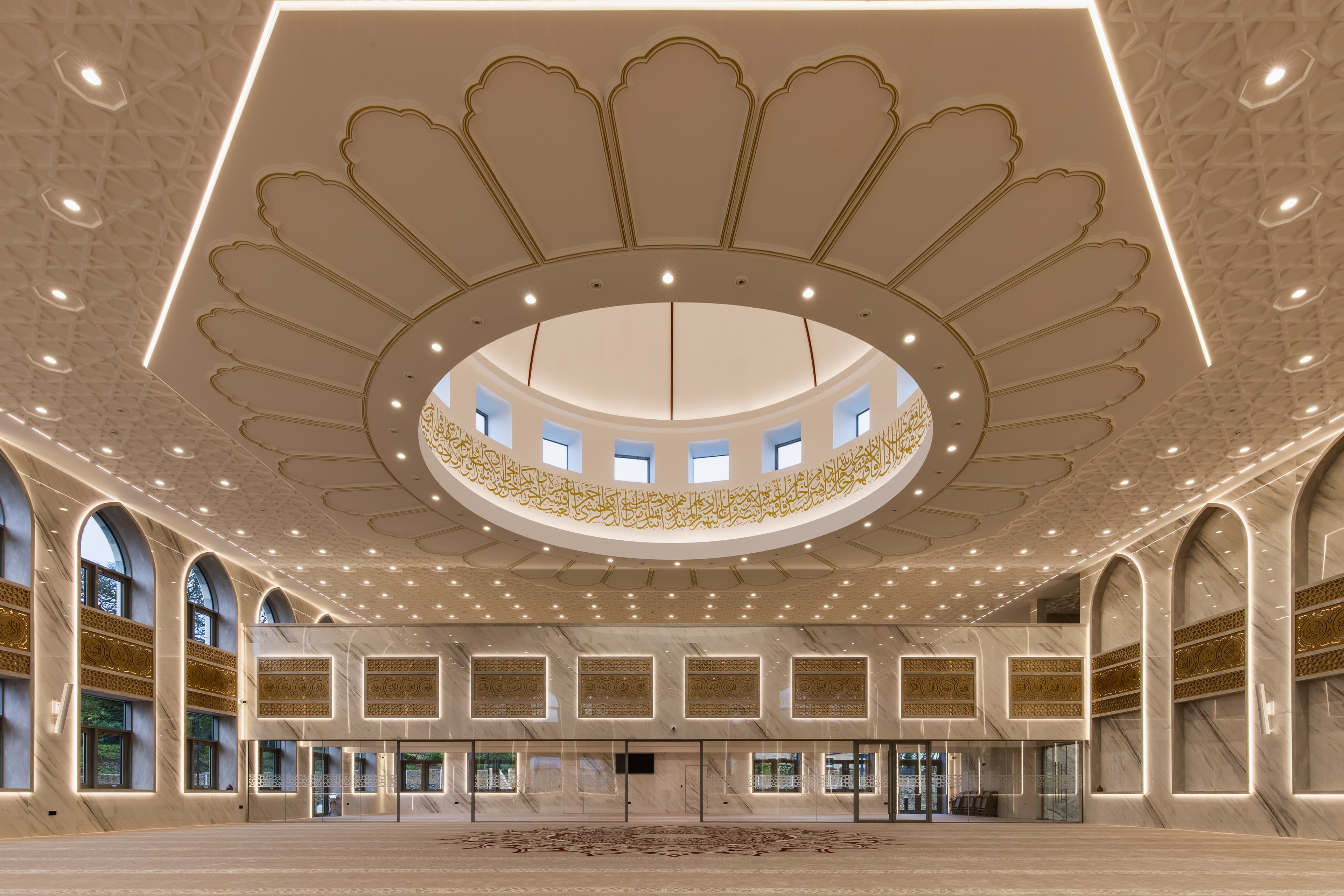 The main prayer hall dome seen from below, with its gold ring of calligraphy and clerestory windows.