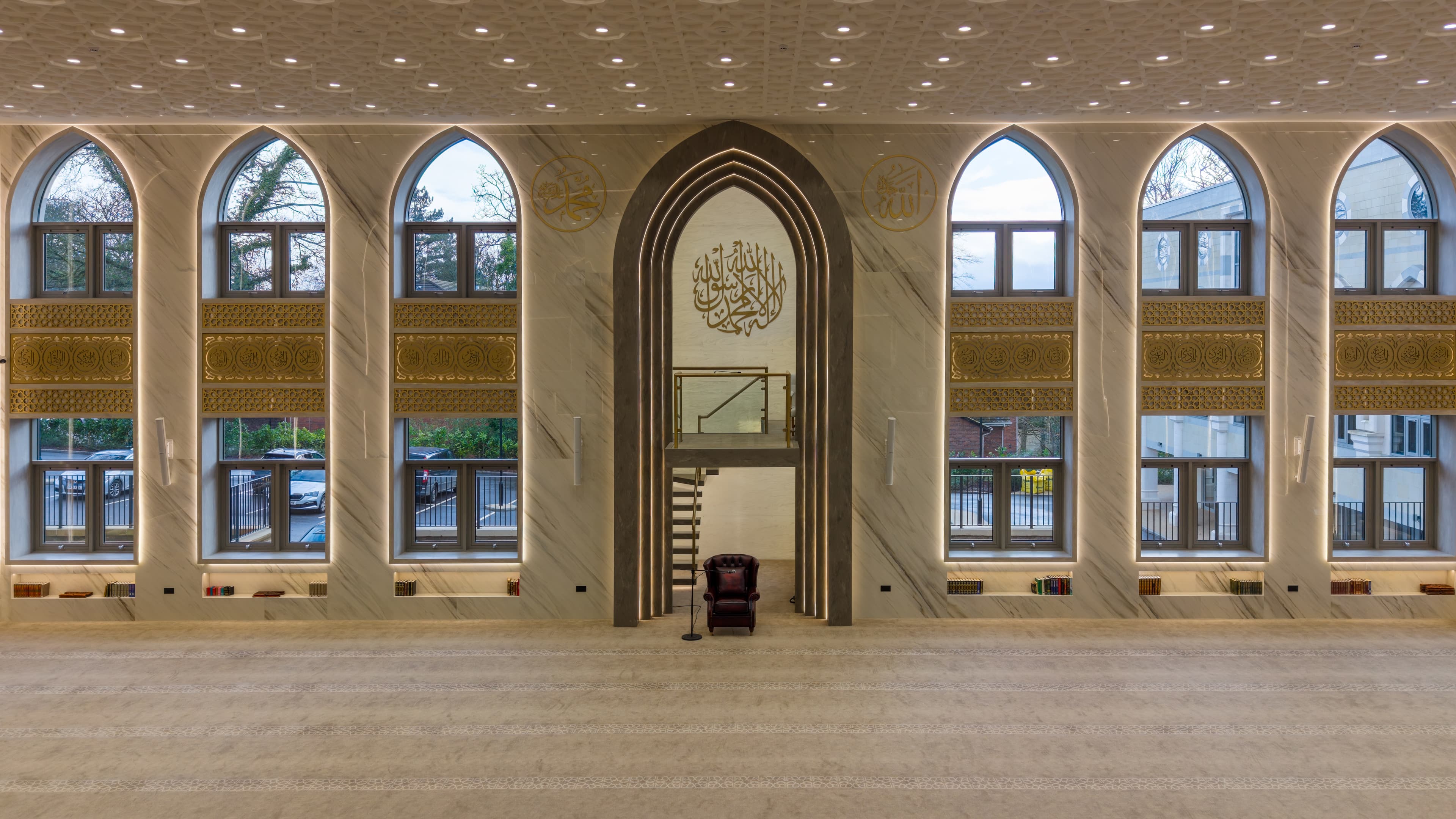 The miḥrāb wall of the prayer hall with arched windows to either side of the central niche.